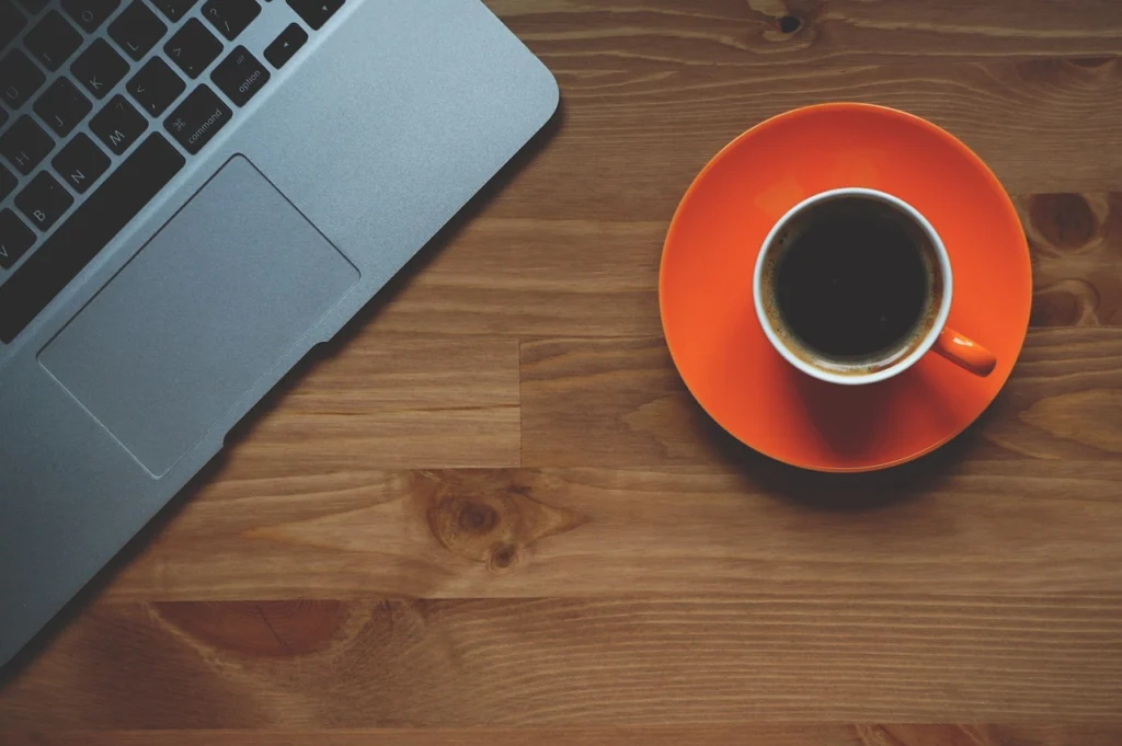Laptop with charts on desk next to coffee
