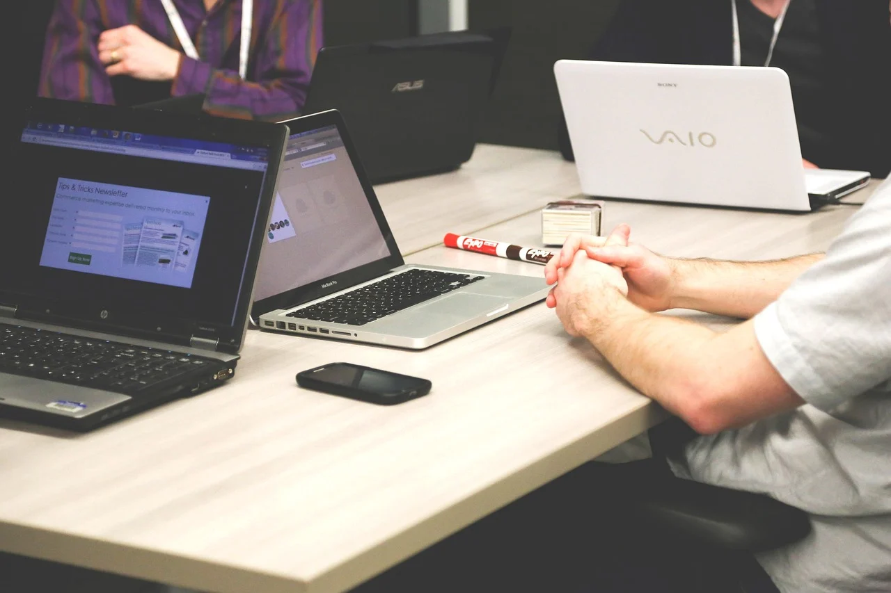 A business team discussing customer retention strategies around a table with laptops